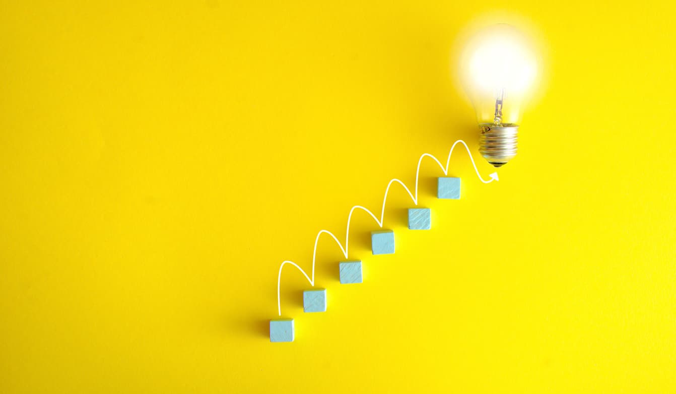 Concept of business growth and creative ideas showing a lit lightbulb at the end of a rising arrow over blue steps. Global Access to America’s Biggest Jackpots